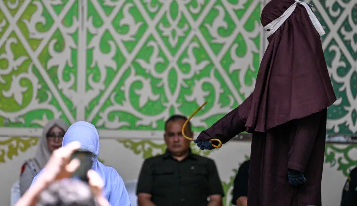 CORRECTION/A woman, part of an unmarried couple seen kissing on a Tiktok livestream, is caned as punishment under sharia law in Banda Aceh on July 2, 2026. Officials in Indonesia's staunchly Islamic Aceh province publicly flogged an unmarried couple on July 2, an AFP reporter witnessed, after the pair kissed in a video posted to social media.  Acts of physical intimacy such as kissing, hugging or touching between men and women who are not husband and wife are forbidden in Aceh, the only province in the Southeast Asian country that applies a version of the Islamic law. (Photo by CHAIDEER MAHYUDDIN/AFP)/?The erroneous mention[s] appearing in the metadata of this photo by CHAIDEER MAHYUDDIN has been modified in AFP systems in the following manner: [clarifying charge and adding context]. Please immediately remove the erroneous mention[s] from all your online services and delete it (them) from your servers. If you have been authorized by AFP to distribute it (them) to third parties, please ensure that the same actions are carried out by them. Failure to promptly comply with these instructions will entail liability on your part for any continued or post notification usage. Therefore we thank you very much for all your attention and prompt action. We are sorry for the inconvenience this notification may cause and remain at your disposal for any further information you may require.?