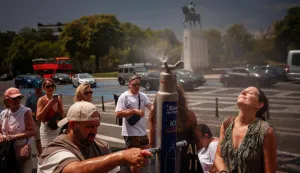 (FILES) People cool off at a mist fountain at Place du Trocadero during a heatwave in Paris on June 26, 2026. France's Prime Minister did not rule out another heat ave, following the exceptional one that hit the country last week, and assured that the measures put in place to deal with this historic heat had indeed ?held up.? (Photo by Dimitar DILKOFF/AFP)