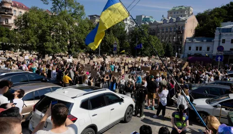 Protesters chant slogans and wave a Ukranian national flag as they take part in a demonstration against Ukraine's President Volodymyr Zelensky's decision to dismiss Ukraine's Defence Minister Mykhailo Fedorov, in Kyiv on July 16, 2026, amid the Russian invasion of Ukraine. Large protests erupted in several Ukrainian cities on July 16 morning against the removal of popular Defence Minister Mykhailo Fedorov. AFP reporters in Kyiv saw more than a thousand people gathered on a central square, singing the Ukrainian national anthem, waving Ukrainian and EU flags and chanting "shame" and "bring Fedorov back". Only appointed six months ago, Fedorov carved a reputation as a moderniser who tried to reform the Ukrainian military, worn down by more than four years of the Russian invasion. (Photo by Tetiana DZHAFAROVA/AFP)