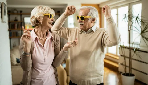 Cheerful senior couple with sunglasses dancing and having fun together at home. stariji par umirovljenici umirovljenik sretni zabava zdravljemagnific.com