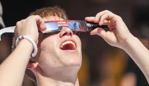 epa06154913 A person takes a look at the sun through his solar eclipse viewing glasses as he arrives in the campus of Southern Illinois University before the start of a total solar eclipse in Carbondale, Illinois, USA, 21 August 2017. The 21 August 2017 total solar eclipse will last a maximum of 2 minutes 43 seconds and the thin path of totality will pass through portions of 14 US states, according to the National Aeronautics and Space Administration (NASA). EPA/TANNEN MAURY