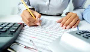 Photo of human hands holding pencil and ticking data in documents računovođa računovodstvo računi novac izvje&scaron;će bilanca 