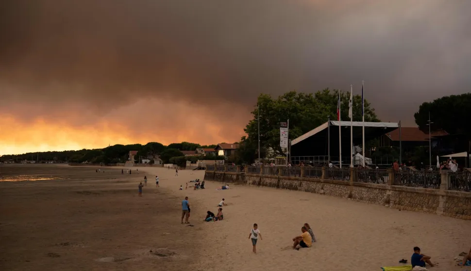 This picture shows people on the beach in Andernos-Les Bains during fire in Lege Cap-Ferret forest, southwestern France on July 23, 2026, as part of the nearby area has been evacuated. A highly virulent wildfire has swept through more than 3700 hectares since July 22 near the Arcachon Basin (Gironde), where nearly 20,000 residents and tourists have been evacuated in total from this area of the Landes de Gascogne forest, already devastated by flames in 2022. (Photo by Olivier MORIN/AFP)