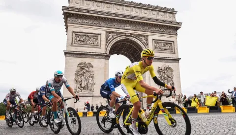 (FILES) This photograph taken on July 27, 2025, shows UAE Team Emirates - XRG team's Slovenian rider Tadej Pogacar wearing the overall leader's yellow jersey cycling with the pack of riders (peloton) past the Arc de Triomphe on Place Charles de Gaulle during the 21st and final stage of the 112th edition of the Tour de France cycling race, 132.3 km between Mantes-la-Ville and Paris' Champs-Elysees Avenue. Tour de France organisers announced on July 25, 2026 that they were shortening the 21st and final final stage of the 2026 edition due to the wildfires ravaging southwest France. The news came after the interior ministry had said that it would need to redeploy officers initially mobilised to provide security for the race, to areas affected by the fire. The 21st stage was due to last 133km and begin west of Paris in Thoiry. Instead, it will start on the Champs Elysees in Paris and take in a couple of extra laps around the famous avenue before joining the main Montmartre circuit, and will last only 89km. (Photo by Anne-Christine POUJOULAT/AFP)