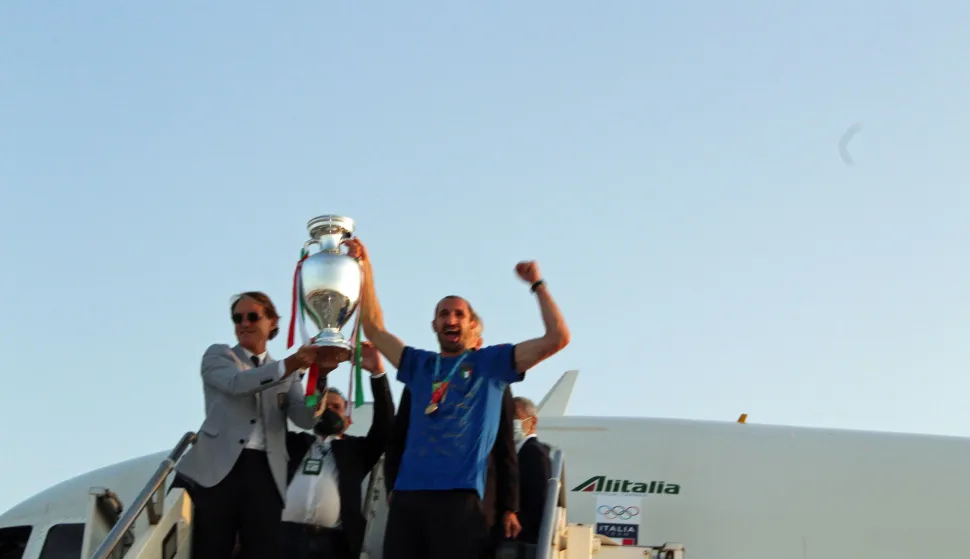 epa09339556 Italy captain Giorgio Chiellini (R) and head coach Roberto Mancini (L) holding the European Championship trophy as the Italian football team returns from London after winning the UEFA EURO 2020 championship, at Rome's Leonardo Da Vinci airport in Fiumicino, Italy, 12 July 2021. EPA/TELENEWS