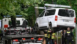 Police get the van lifted on a truck to remove it on July 26, 2026 in the Tiergatren Park in Berlin, after it was used in the car-ramming attack in the Tiergarten park that left one woman dead and 29 other people injured on the sidelines of the Christopher Street Day (CSD) parade the evening before. German police on July 26, 2026 were hunting for the prime suspect in what authorities called an Islamist terror attack on the outskirts of Berlin Pride late on July 25, 2026. The incident shattered what had been a day of celebration for hundreds of thousands attending Christopher Street Day (CSD), one of Europe's largest Pride events. (Photo by RALF HIRSCHBERGER/AFP)