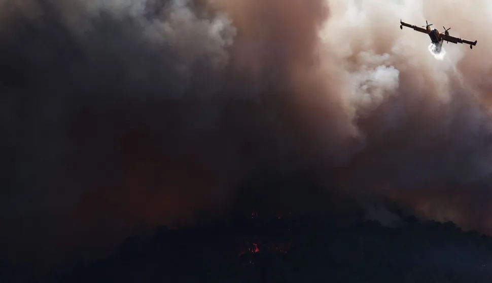 (FILES) A French Civil Security Canadair CL-415 aircraft sprays water on a forest surrounding Cotignac, southeastern France on July 23, 2026 during a wildfire. France has been battered by three heatwaves since May as part of increasingly common extreme weather episodes linked to climate change, causing thousands of excess deaths and fuelling wildfires. (Photo by Thibaud MORITZ/AFP)