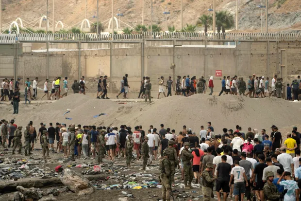 Spanish soldiers control as migrants cross back to Morocco after they crossed the border to enter Spain's north Africa's Ceuta enclave on July 31, 2026. Thousands of migrants crossed overnight from Morocco into Ceuta enclave, a police source said, as Spanish Prime Minister was set to arrive to manage the latest migrant crisis on the border. In recent days, a total of around 40,000 migrants have crossed into the territory, population 80,000, the source added. (Photo by JORGE GUERRERO/AFP)