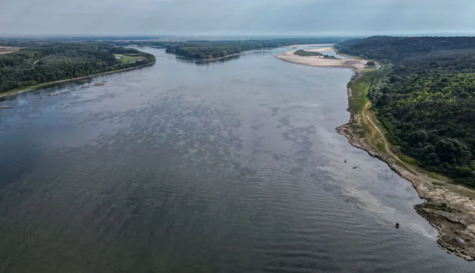 An aerial view shows the splitting point of Danube with Bala branch (L) and Old Danube (R), the place where a controlled underwater explosion took place on the riverbed of the Danube River in Izvoarele village, on August 3, 2026. The blast aimed at deepening the channel and diverting a higher volume of water toward the cooling systems of the Cernavoda Nuclear Power Plant. Local authorities and plant engineers authorized the blasting operations to counteract critically low water levels caused by a prolonged summer heatwave, ensuring the continuous and safe operation of the facility's reactors. (Photo by Daniel MIHAILESCU/AFP)