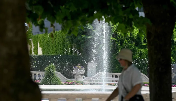 A tourist walks under trees past a fountain at the Mirabell Gardens in Salzburg, Austria on July 31, 2026, where temperatures are expected to reach 36 degrees Celsius. (Photo by BARBARA GINDL/APA/AFP)/Austria OUT