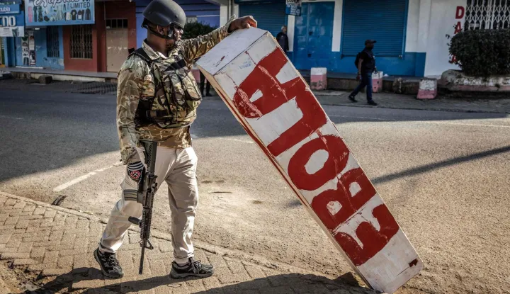 A Kenyan police officer holds a mock coffin abandoned in a street by protesters during a demonstration against a controversial US-built Ebola quarantine centre slated to begin operations at Laikipia Air Base in Nanyuki on June 9, 2026. Several Kenyans were arrested on June 9, 2026 in the latest protests against an Ebola quarantine centre being built for US citizens in a tourist town.The centre at Laikipia Air Base in the town of Nanyuki, under the shadow of Mount Kenya, is set to quarantine Americans arriving from the Democratic Republic of Congo (DRC), which is battling a major Ebola outbreak. (Photo by Luis TATO/AFP)