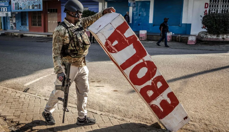 A Kenyan police officer holds a mock coffin abandoned in a street by protesters during a demonstration against a controversial US-built Ebola quarantine centre slated to begin operations at Laikipia Air Base in Nanyuki on June 9, 2026. Several Kenyans were arrested on June 9, 2026 in the latest protests against an Ebola quarantine centre being built for US citizens in a tourist town.The centre at Laikipia Air Base in the town of Nanyuki, under the shadow of Mount Kenya, is set to quarantine Americans arriving from the Democratic Republic of Congo (DRC), which is battling a major Ebola outbreak. (Photo by Luis TATO/AFP)