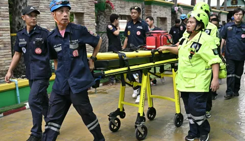 Emergency responders walk with a stretcher outside a school following a shooting in Bang Kruai district, Nonthaburi province, north of Thailand's capital Bangkok, on August 7, 2026. At least two people were killed and several others wounded in a school shooting north of the Thai capital Bangkok on August 7, a Nonthaburi provincial official told AFP. (Photo by Lillian SUWANRUMPHA/AFP)