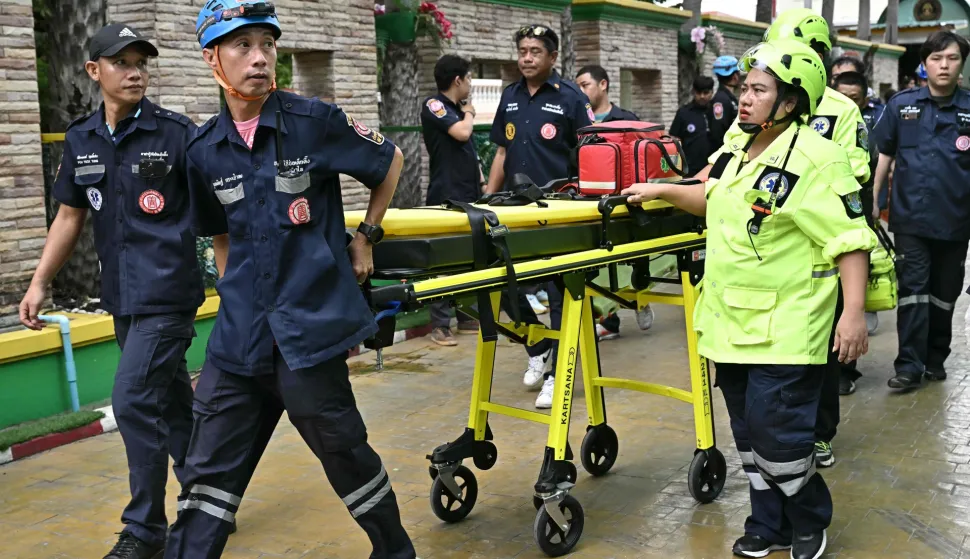 Emergency responders walk with a stretcher outside a school following a shooting in Bang Kruai district, Nonthaburi province, north of Thailand's capital Bangkok, on August 7, 2026. At least two people were killed and several others wounded in a school shooting north of the Thai capital Bangkok on August 7, a Nonthaburi provincial official told AFP. (Photo by Lillian SUWANRUMPHA/AFP)
