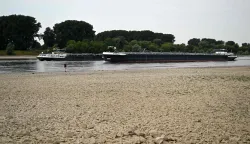 Cargo ships navitage on the water of the Rhine as the partially dried-up river bed is seen in the foreground near Leverkusen, western Germany on July 30, 2026, following exceptionally hot weather. (Photo by Ina FASSBENDER/AFP)