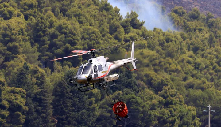 A helicopter drops water over a burning area as a wildfire flares in Sagana in the territory of Monreale, Sicily on July 22, 2026. (Photo by Alessandro FUCARINI/AFP)