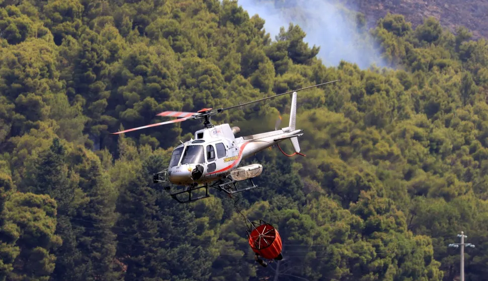 A helicopter drops water over a burning area as a wildfire flares in Sagana in the territory of Monreale, Sicily on July 22, 2026. (Photo by Alessandro FUCARINI/AFP)