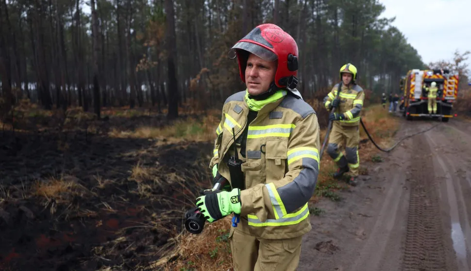 Ukrainian firefighters aiding in the fight against France's ongoing wildfires work to put out smouldering vegetation near the village of Le Temple, southwestern France, on August 3, 2026. A massive fire in the near the Arcachon Bay in the Gironde department started on July 22, forcing 220 people to flee their homes to safety. The fire went on to incinerate some 42,000 hectares (104,000 acres) of pine forest along the Atlantic coastline, destroying some 240 homes in its wake. (Photo by ROMAIN PERROCHEAU/AFP)
