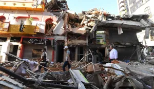 People walk past the rubble of a collapsed building after an earthquake in Pereira, Colombia on August 11, 2026. (Photo by Jaime SALDARRIAGA/AFP)