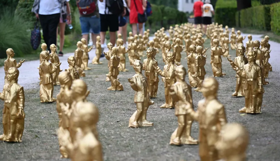 Visitors walk past an art installation called "Mozart - The Unconquerable Genius" by German conceptual artist Ottmar Hoerl with hundreds of golden figurines featuring Austrian composer Wolfgang Amadeus Mozart at the Mirabell Gardens in Salzburg, Austria, on July 14, 2026. From mid-July to the end of August 2026, around the installation with 400 golden Mozart figurines will be displayed at the Mirabell Gardens to celebrate the 270 birthday of Mozart who was born on January 27, 1756 in Salzburg. (Photo by BARBARA GINDL/APA/AFP)/Austria OUTRESTRICTED TO EDITORIAL USE - MANDATORY MENTION OF THE ARTIST UPON PUBLICATION - TO ILLUSTRATE THE EVENT AS SPECIFIED IN THE CAPTION