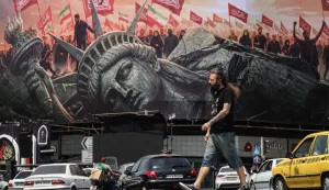 An Iranian man walks past an anti-US billboard at Enghelab Square in central Tehran on August 3, 2026. Iran denied any negotiations were taking place with the United States after the US president said new talks would begin on August 3 in an effort to end their war, now in its sixth month. Washington and Tehran have been at war since February 28, when the US and Israel launched surprise strikes against Iran, though months of on-off diplomacy have led to periods of relative calm. (Photo by ATTA KENARE/AFP)/