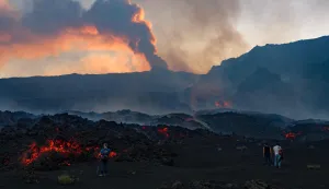 This handout photograph taken by Etna Walk on August 11, 2026 and obtained on August 12, 2026 shows visitors standing next to lava flowing from Mount Etna volcano during an eruption, in Catania, in the Mediterranean island of Sicily. (Photo by Handout/Etna Walk/AFP)/RESTRICTED TO EDITORIAL USE - MANDATORY CREDIT "AFP PHOTO/ETNA WALK /" - NO MARKETING NO ADVERTISING CAMPAIGNS - DISTRIBUTED AS A SERVICE TO CLIENTS