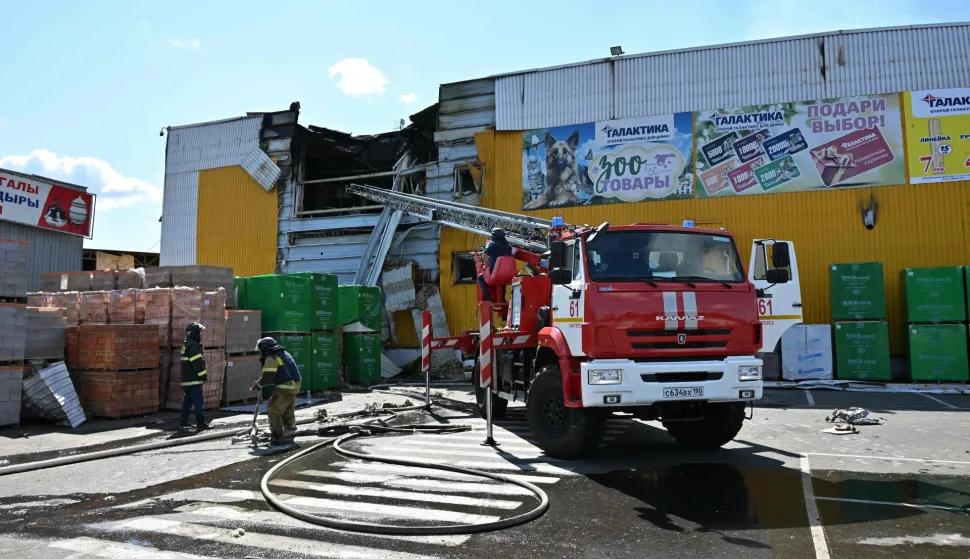 Firefighters work on the grounds of a burned DIY and construction materials mall following an overnight attack, which local Russian-installed officials called Ukrainian drone strikes, in Yenakiyeve in the Donetsk region, Russian-controlled Ukraine, on August 14, 2026, amid the ongoing Russian-Ukrainian conflict. (Photo by AFP)