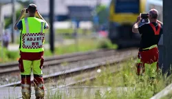 Emergency services take images with their smartphones at the site of an accident after a train crashed into a school bus, at the railway crossing Vierhuizen in Buggenhout on May 26, 2026. (Photo by DIRK WAEM/BELGA/AFP)/Belgium OUT