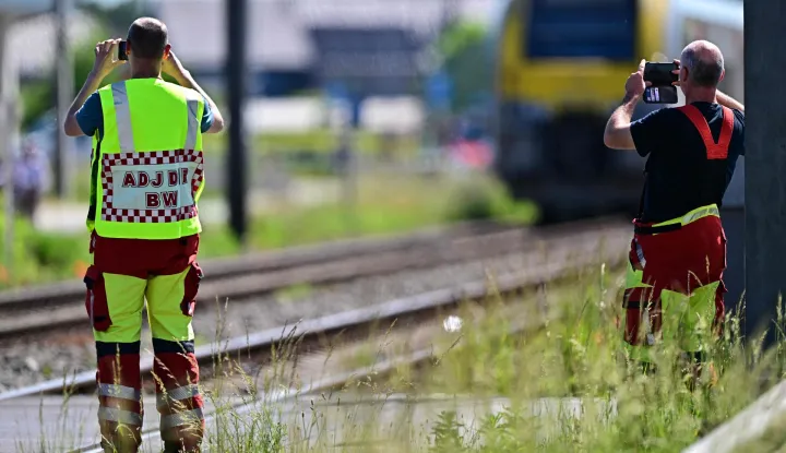 Emergency services take images with their smartphones at the site of an accident after a train crashed into a school bus, at the railway crossing Vierhuizen in Buggenhout on May 26, 2026. (Photo by DIRK WAEM/BELGA/AFP)/Belgium OUT