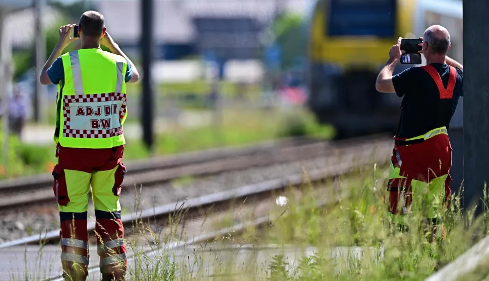Emergency services take images with their smartphones at the site of an accident after a train crashed into a school bus, at the railway crossing Vierhuizen in Buggenhout on May 26, 2026. (Photo by DIRK WAEM/BELGA/AFP)/Belgium OUT