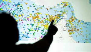 (FILES) A photo illustration taken in Nicosia on May 4, 2026, shows a person in front of a large screen displaying vessel movements in the Strait of Hormuz on a ship-tracking website. Iran on August 15, 2026, fired back at the US president's claim that he would soon declare the Strait of Hormuz part of US territory, saying the crucial energy waterway it has blockaded "will remain Iranian". Last week, a top Iranian official laid out a laundry list of conditions for reopening the strait, including an end to the "war and aggression against Iran and its allies in Lebanon, Palestine, Yemen, and Iraq". (Photo by AFP)