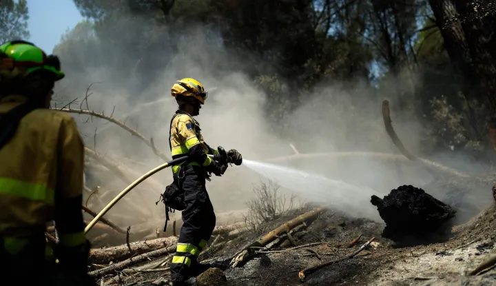CORRECTION/Firefighters douse the ground to prevent reignition after a wildfire was brought under control near La Adrada, 95 kilometres west of Madrid, on July 28, 2026. Spanish Prime Minister Pedro Sanchez said today that the country is starting to see the light at the "end of the tunnel in the fight against these wildfires," although he warned of "particularly complex hours" ahead as a new heatwave is set to hit the country starting tomorrow. The provinces of Avila, Madrid, Toledo, and Castellon continue to battle wildfires that have already burned over 77,000 hectares and forced the preventive evacuation of 63,000 people, according to figures from the Ministry of the Interior. (Photo by Oscar DEL POZO/AFP)/?The erroneous caption appearing in the metadata of this photo by Oscar DEL POZO has been modified in AFP systems in the following manner: [Firefighters douse the ground to prevent reignition after a wildfire was brought under control near La Adrada, 95 kilometres west of Madrid, on July 28, 2026.] instead of [This picture shows a burnt-out house in the residential area of Santa Barbara in La Vilavella, 50 kilometres north of Valencia, on July 28, 2026.]. Please immediately remove the erroneous mention[s] from all your online services and delete it (them) from your servers. If you have been authorized by AFP to distribute it (them) to third parties, please ensure that the same actions are carried out by them. Failure to promptly comply with these instructions will entail liability on your part for any continued or post notification usage. Therefore we thank you very much for all your attention and prompt action. We are sorry for the inconvenience this notification may cause and remain at your disposal for any further information you may require.?