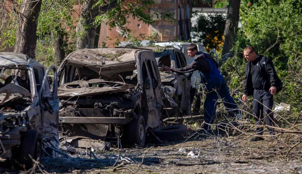 Two men inspect destroyed cars at the site of an air attack in Dnipro on June 2, 2026, amid the Russian invasion of Ukraine. Russia pummelled Ukraine with hundreds of drones and dozens of missiles early on June 2, 2026, killing at least 11 people, after threatening a large-scale attack and warning foreign citizens to leave Kyiv. (Photo by Mykola SYNELNYKOV/AFP)