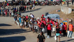 Red Cross volunteers distribute food to migrants who remain living on the streets, in Trampolin beach in Ceuta, on August 22, 2026. Some 72,000 migrants breached the border in an unprecedented and deadly rush into the north African territory on July 30-31, with 70,000 having since returned to Morocco, according to Spanish government figures. (Photo by Antonio Sempere/AFP)