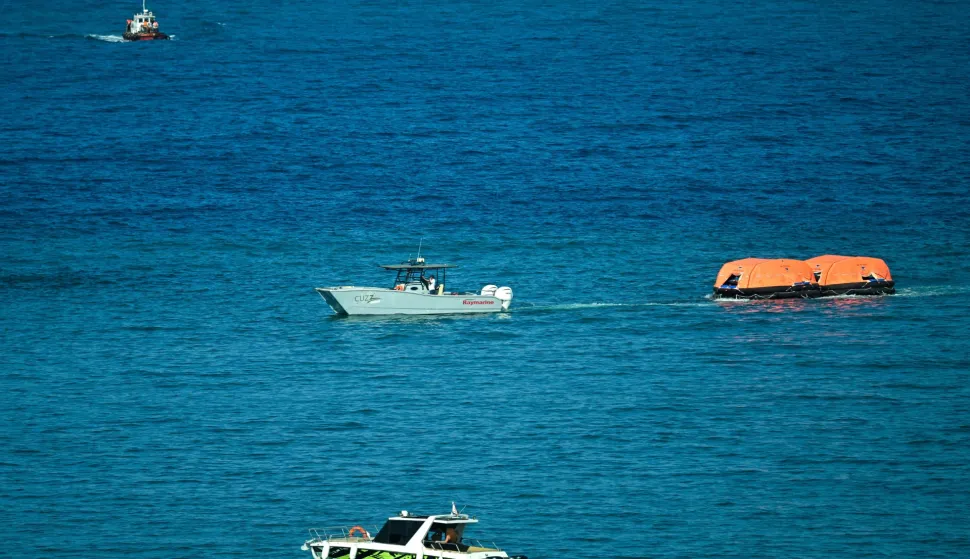 A vessel tows rescue rafts during a rescue operation off the coast of Kyrenia, in the self-proclaimed Turkish Republic of Northern Cyprus (TRNC), recognised only by Turkey, on August 30, 2026, after a ferry capsized. A passenger ferry capsized and sank off Northern Cyprus on August 30, killing at least seven people and leaving 23 missing, officials said, as a rescue operation was under way. The cause was not yet established. But one rescued passenger told local media a blast went off at the bow of the ferry before it rolled over. (Photo by Jewel SAMAD/AFP)