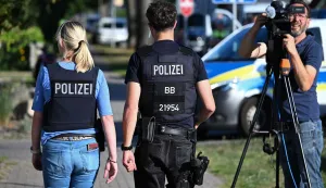 Police officers walk near the scene at a school in Gosen-Neu Zittau, south-east of Berlin on August 27, 2026, after two people were killed in a "violent incident" at the school. Local media reported August 27 that an 18-year-old female student and a 30-year-old man had died. Regional public broadcaster RBB and a local daily said that an alarm had been triggered at a secondary school in the town of Gosen-Neu Zittau, with police confirming they were on the scene and that a suspect had been arrested. (Photo by RALF HIRSCHBERGER/AFP)