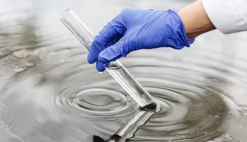 Researcher holds a test tube with water in a hand in blue glovezagađenje voda ekologija industrija kemikalije okoli&scaron;magnific