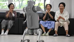 This picture taken on August 13, 2026 shows elderly people playing with a robot dog during a government-organised digital survival training at a senior community centre in Suwon. Age gaps in digital literacy are a global concern, yet the gulf has widened massively in the hyper-connected and fast-aging country, prompting national campaigns to bridge it. (Photo by Jung Yeon-je/AFP)/TO GO WITH AFP STORY SKorea-demographics-computers/FOCUS BY Hawon Jung