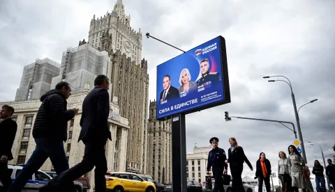 Pedestrians walk past the Russian Foreign Ministry building and a campaign poster for the election to the Russian State Duma (lower house of Russia's Parliament) in Moscow on September 7, 2026. Russia will vote for the Duma's election on September 18-20, 2026. (Photo by Alexander NEMENOV/AFP)