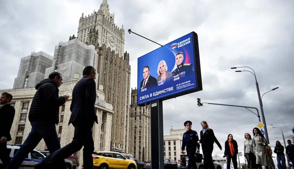 Pedestrians walk past the Russian Foreign Ministry building and a campaign poster for the election to the Russian State Duma (lower house of Russia's Parliament) in Moscow on September 7, 2026. Russia will vote for the Duma's election on September 18-20, 2026. (Photo by Alexander NEMENOV/AFP)