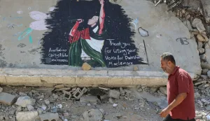 A Palestinian man walks past a mural painted on the rubble of a destroyed building and dedicated to US rapper, singer, dancer and DJ, Benjamin Haggerty, known as Macklemore, in Gaza City on September 19, 2026. Macklemore was booted from Ed Sheeran's US tour after provoking outrage by saying "free Palestine" at one of the stadium stops this month, the US rapper said on September 14. The artist made headlines after telling the crowd at MetLife Stadium in New Jersey that he wanted the people of Gaza and the West Bank to know they had not been forgotten. (Photo by Omar AL-QATTAA/AFP)