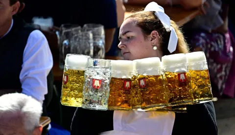 A waitress serves beer in mugs after the start Munich's annual beer festival, the Oktoberfest, in Munich, southern Germany on September 19, 2026. The world's biggest beer festival Oktoberfest runs until October 4, 2026. (Photo by Tobias SCHWARZ/AFP)