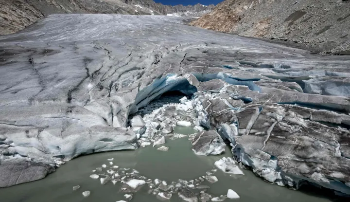 (FILES) This photograph shows a group of hikers making their way past a melt hole on the melting Rh?ne Glacier, above Gletsch in the Swiss Alps, on July 24, 2026. Swiss glaciers have lost nearly 20% of their volume over the past five years, including 5.5% this year, following a record-hot summer and low winter snowfall, according to data from the Swiss Glacier Monitoring Network (Glamos) published on October 1, 2026. (Photo by Fabrice COFFRINI/AFP)