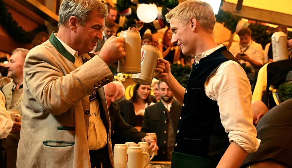 Bavaria's State Premier Markus Soeder (L) and the mayor of Munich Dominik Krause clink their beer mugs after the first barrel of beer was tapped with the traditional "O?zapft is!" (It's tapped!) to start Munich's annual beer festival, the Oktoberfest, on September 19, 2026 in Munich, southern Germany. The world's biggest beer festival Oktoberfest runs until October 4, 2026. (Photo by Tobias SCHWARZ/AFP)