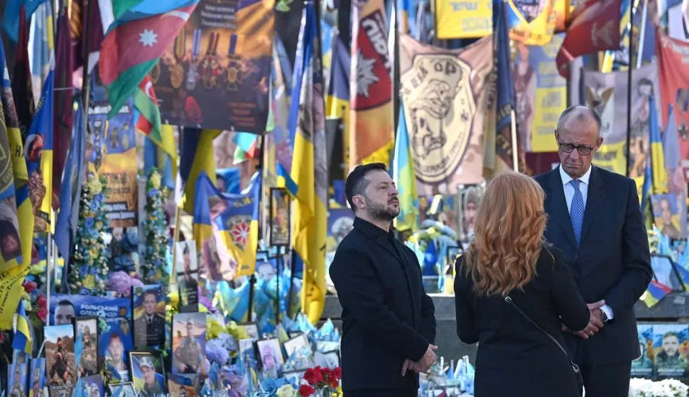 TOPSHOT - Ukraine's President Volodymyr Zelensky (L) and Germany's Chancellor Friedrich Merz (R) stand next to a makeshift memorial for Ukrainian and foreign soldiers on Independence Square in Kyiv on October 4, 2026, amid the Russian invasion of Ukraine. (Photo by Sergei SUPINSKY/AFP)