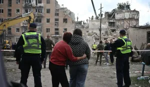 TOPSHOT - Local residents hug as they look at a multi-floor residential building destroyed following a Russian aerial strike in Pryluky on October 7, 2026, amid the Russian invasion of Ukraine. In Pryluky, the death toll has risen to nine people, including three children, and 40 people are known to have been injured, including seven children, the Emergency Service said on October 7, 2026. (Photo by Genya Savilov/AFP)