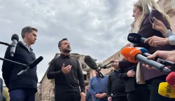 Ukraine's President Volodymyr Zelensky (C) and Britain's Foreign Secretary Ed Miliband (L) speak to the press outside a multi-storey residential building in Pryluky, on October 8, 2026, the day following its destruction during a Russian aerial attack, amid the Russian invasion of Ukraine. (Photo by Sergii VOLSKYI/AFP)