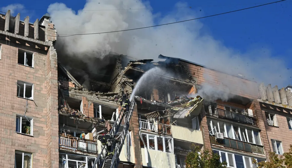 Firefighters work at a residential building damaged in a Russian drone strike in Kharkiv on October 12, 2026, amid the Russian invasion of Ukraine. (Photo by SERGEY BOBOK/AFP)
