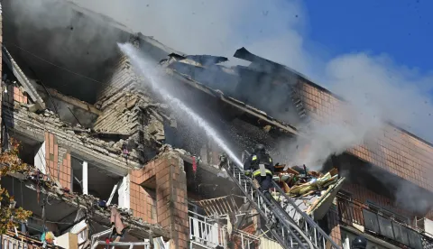 Firefighters work at a residential building damaged in a Russian drone strike in Kharkiv on October 12, 2026, amid the Russian invasion of Ukraine. (Photo by SERGEY BOBOK/AFP)