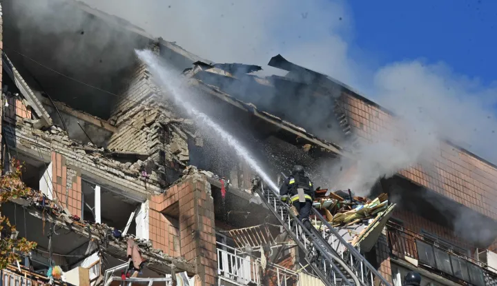 Firefighters work at a residential building damaged in a Russian drone strike in Kharkiv on October 12, 2026, amid the Russian invasion of Ukraine. (Photo by SERGEY BOBOK/AFP)